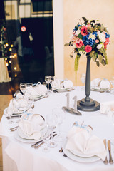 Table set for wedding or another catered event dinner. Decoration arch flowers gift box.