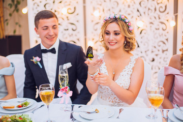 Newlyweds get an original gift butterfly from mother. Shocked and smiling bride. Holding butterfly