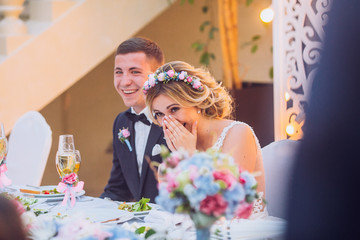 Emotional beautiful newlywed couple smiling and kissing at wedding reception - obrazy, fototapety, plakaty