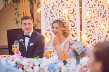 Emotional beautiful newlywed couple smiling and kissing at wedding reception