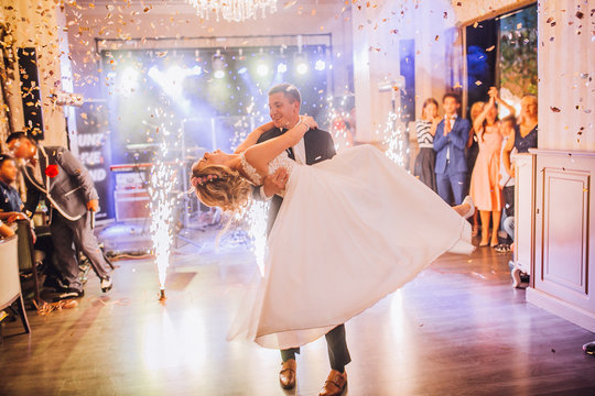 Bride and groom first dance at wedding reception with firewoks and confetti. Kissing and swing couple in love.