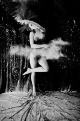 Girl dancer jumping and dancing in the white dust with flour on