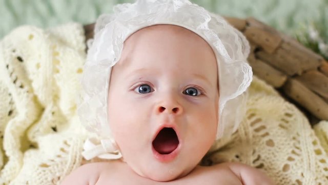 girl kid naked in a white cap lying in the basket and looks at parents