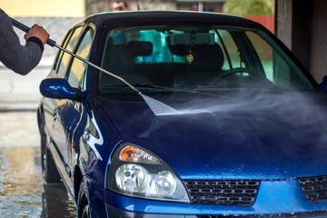 Car Wash Closeup. Washing Car by High Pressure Water