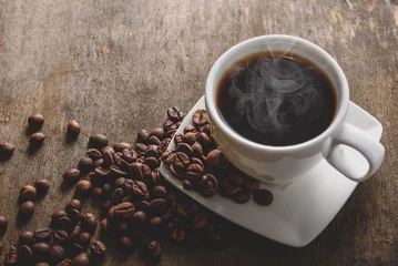 Foto op Plexiglas Fragrant hot coffee in a white cup with beans spilling roasted c © Kryuchka Yaroslav