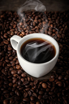 Fototapeta White cup of hot coffee on a background coffee beans.