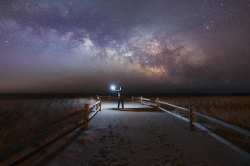 Man under the milky way on a beach path 
