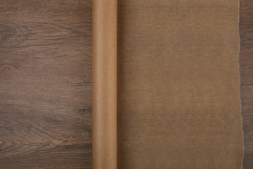 Baking paper on wooden background top view. Roll of butter paper on table with empty place for your design.