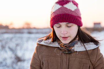 Teenage girl enjoys bright sunset lights in winter