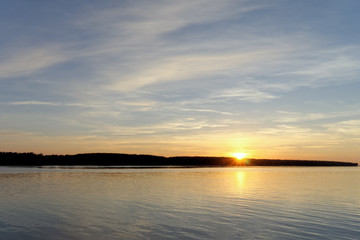 A view of the calm golden sunset on the river with the sun reflected in it, Volga, Russia