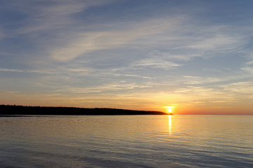 A view of the calm golden sunset on the river with the sun reflected in it, Volga, Russia