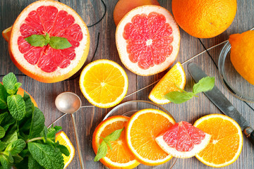 Citrus fruits - grape fruit, lemon, orange - and mint leaves on wooden tables. Top view.