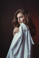 Glorious young model posing in men's shirt in the shadows