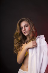 Splendid young woman posing in men's shirt in the shadows