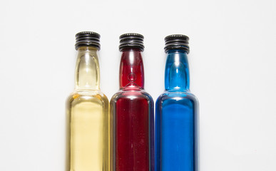 Three transparent bottles with colorful juices,white background.