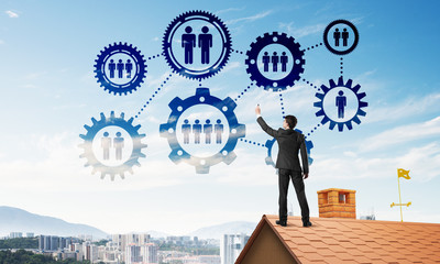 Businessman on house roof presenting teamwork and connection concept. Mixed media