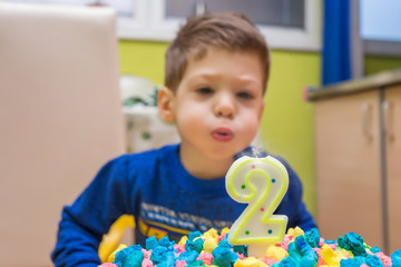 two years old boy blowing candle on birthday cake