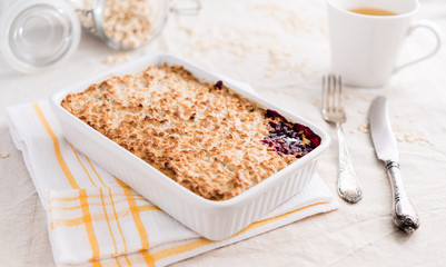 Oat blackcurrant crumble and cup of tea on a bright background. Eating healthy breakfast concept. 