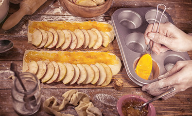 Woman hands cooking dessert with apples, cinnamon and lemon jam on a wooden table. Vintage toning.