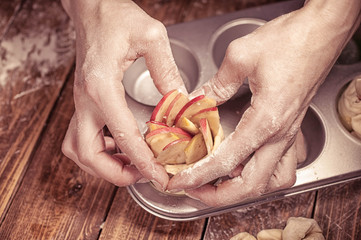 Woman hands cooking dessert with apples, cinnamon and lemon jam on a wooden table. Vintage toning.