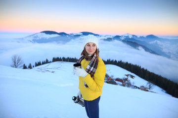 Fototapeta na wymiar Young woman hiking in winter mountains. Woman drinking warm tea in the mountai.