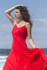 Fototapeta na wymiar Portrait of beautiful woman in red dress in front of the beach.