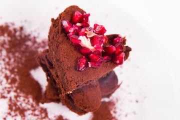 Heart shaped slices of a brownie decorated with pomegranate on white background
