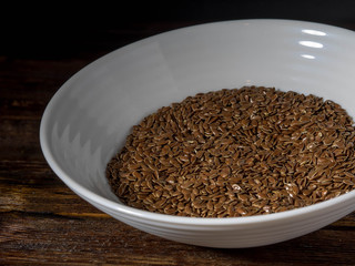 Linen seeds in a little bowl on wooden table
