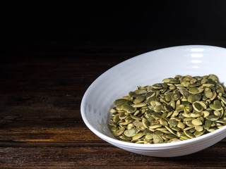Pumpkin seeds in a little bowl on wooden table
