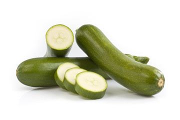 Three green zucchini with cutted pieces, isolated on white background. Still-life picture taken in studio with soft-box.