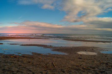 Sunset on beach. sea landscape, wirh red sky and clouds. Beach with waves and rocks, 