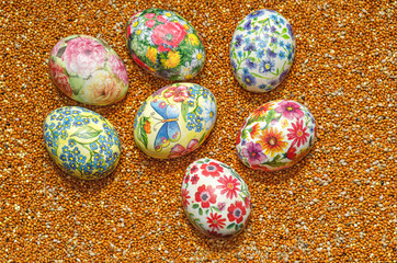 Decoupage handmade Easter eggs on a background of scattered millet