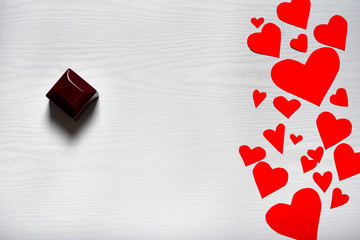 Wooden white background with red hearts and a box with a wedding