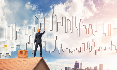 Man architect draw silhouette of modern city on blue sky. Mixed 
