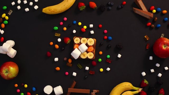 CLOSE UP FOOD: sweet sandwich with candies, and nutella on a black background 