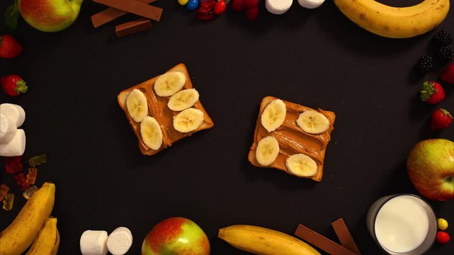 CLOSE UP FOOD: crazy sweet sandwich with candies, fruits, nutella and milk on a black background 