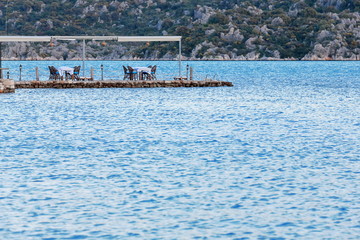 Fototapeta na wymiar Restaurant tables on a jetty in the harbor. Uçagiz-Turkey. 0789