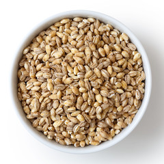 Dry pearl barley in white ceramic bowl isolated on white.