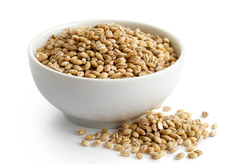 Dry pearl barley in white ceramic bowl isolated on white. 