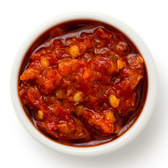 Red chopped chilli peppers in oil in ceramic white bowl.