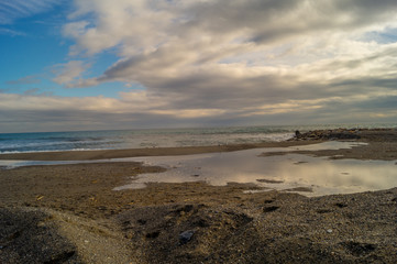 Fototapeta na wymiar sea landscape. Beach with waves and rocks, sky with clouds and sun.