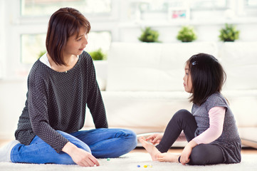 Pretty happy japanese mother play with little daughter at home