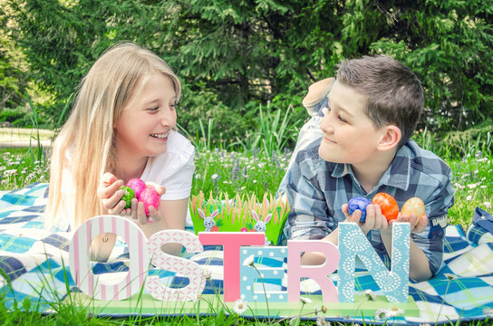 Children in the park with easter eggs in their hands and a decorative inscription Easter in German