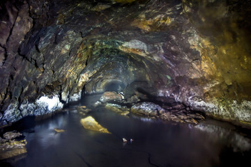 The tunnel of an old abandoned mine with rusty remnants of trolleys