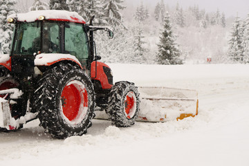Red snowblower grader clears snow covered ski resort road in mountains or city street. Winter...