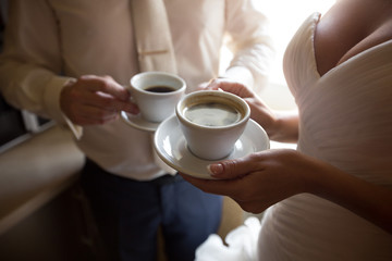 Wedding coffee. Bride and groom holding cups of coffee in morning before wedding ceremony