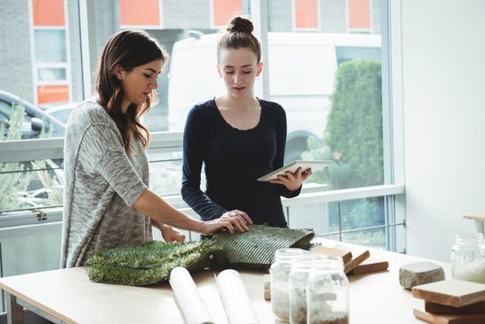 Business executives examining artificial turf while using digital tablet in office - Powered by Adobe