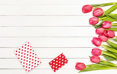 Valentines Day background. Bouquet of pink tulips on white wooden table decorated with gift boxes. Top view, copy space.