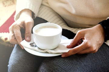 Woman keeping cappuccino on her legs