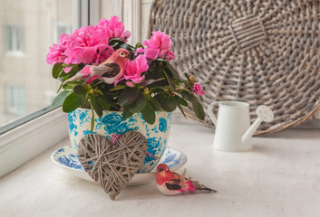 Pink azalea and birds  in a vintage pot on a window